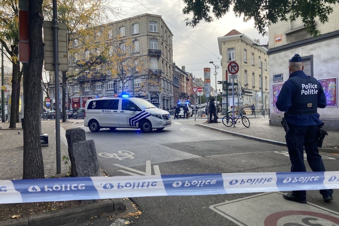 Die Polizei sperrt eine Straße, während ein Polizist hinter Absperrband Wache steht.