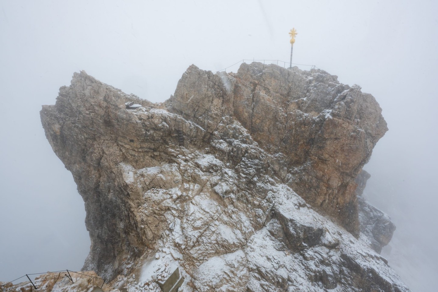 Nebelwolken umhüllen bei Schneetreiben auf der Zugspitze die Aussichtsplattform mit dem Gipfelkreuz (Archivbild). Aus mehreren Bergsteigergruppen wurden Notrufe abgesetzt, nachdem sie aufg...