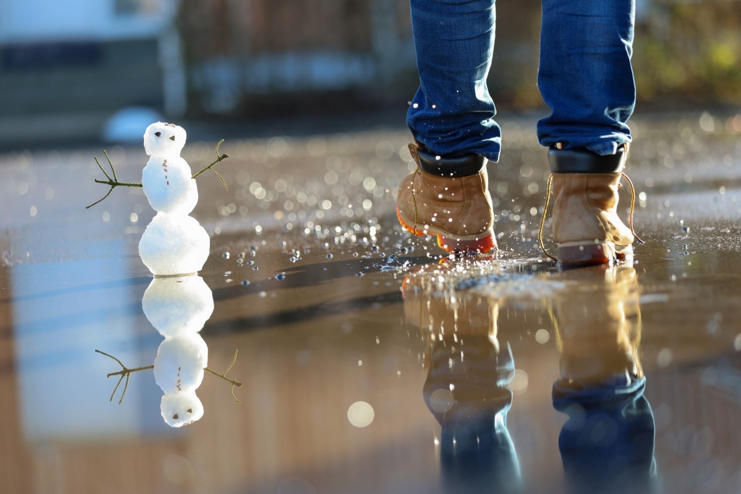 Ein kleiner Schneemann in einer Pfütze.