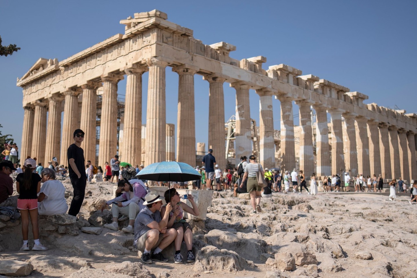 Eine Touristin trinkt Wasser unter einem Sonnenschirm in der Hitze von Athen.