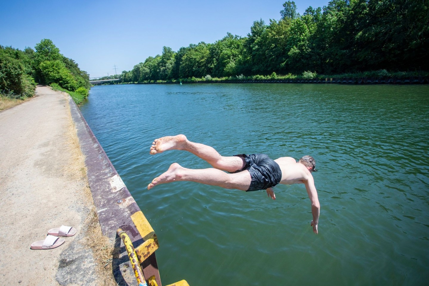 Ein junger Mann springt bei hochsommerlichem Wetter in den Rhein-Herne-Kanal.