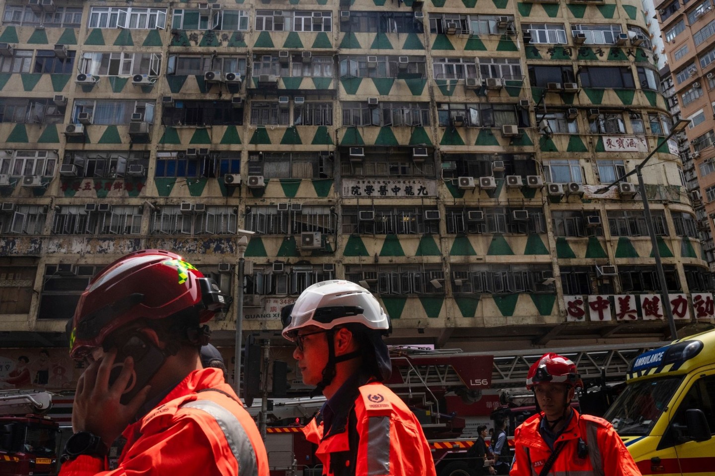 Im Hintergrund ist das ausgebrannte Hochhaus in Hongkong zu sehen - bei der Feuerwehr waren zahlreiche Hilferufe eingegangen.