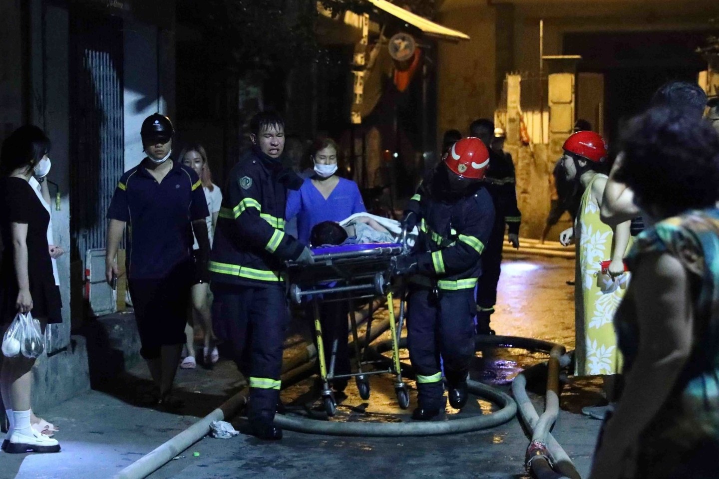 Rettungskräfte tragen eine Person aus dem brennenden Gebäude in Hanoi.