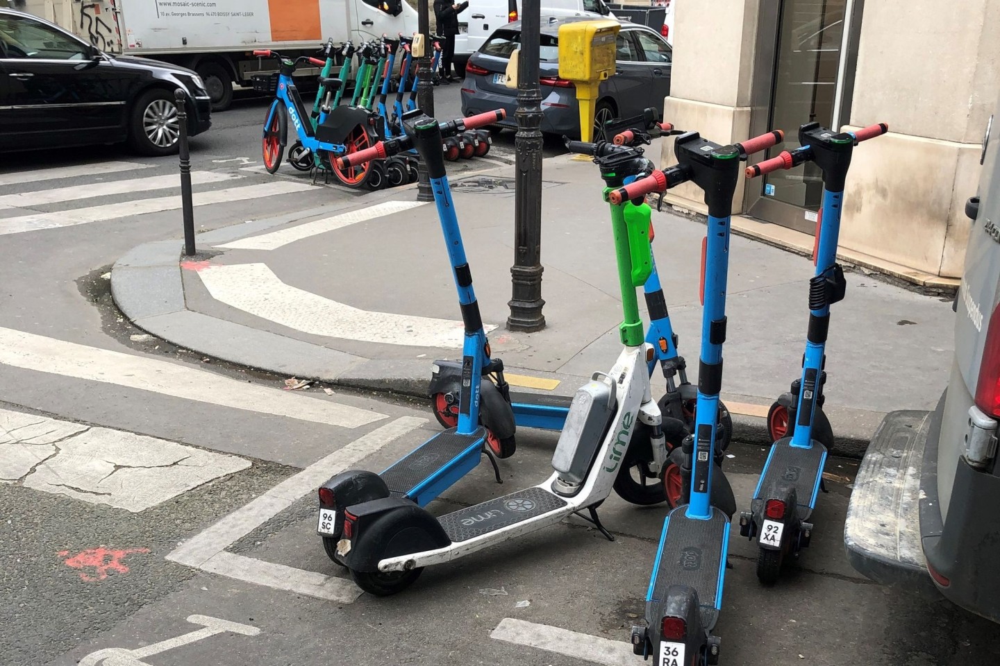 E-Scooter von drei verschiedenen Anbietern stehen auf dafür vorgesehenen Parkplätzen.