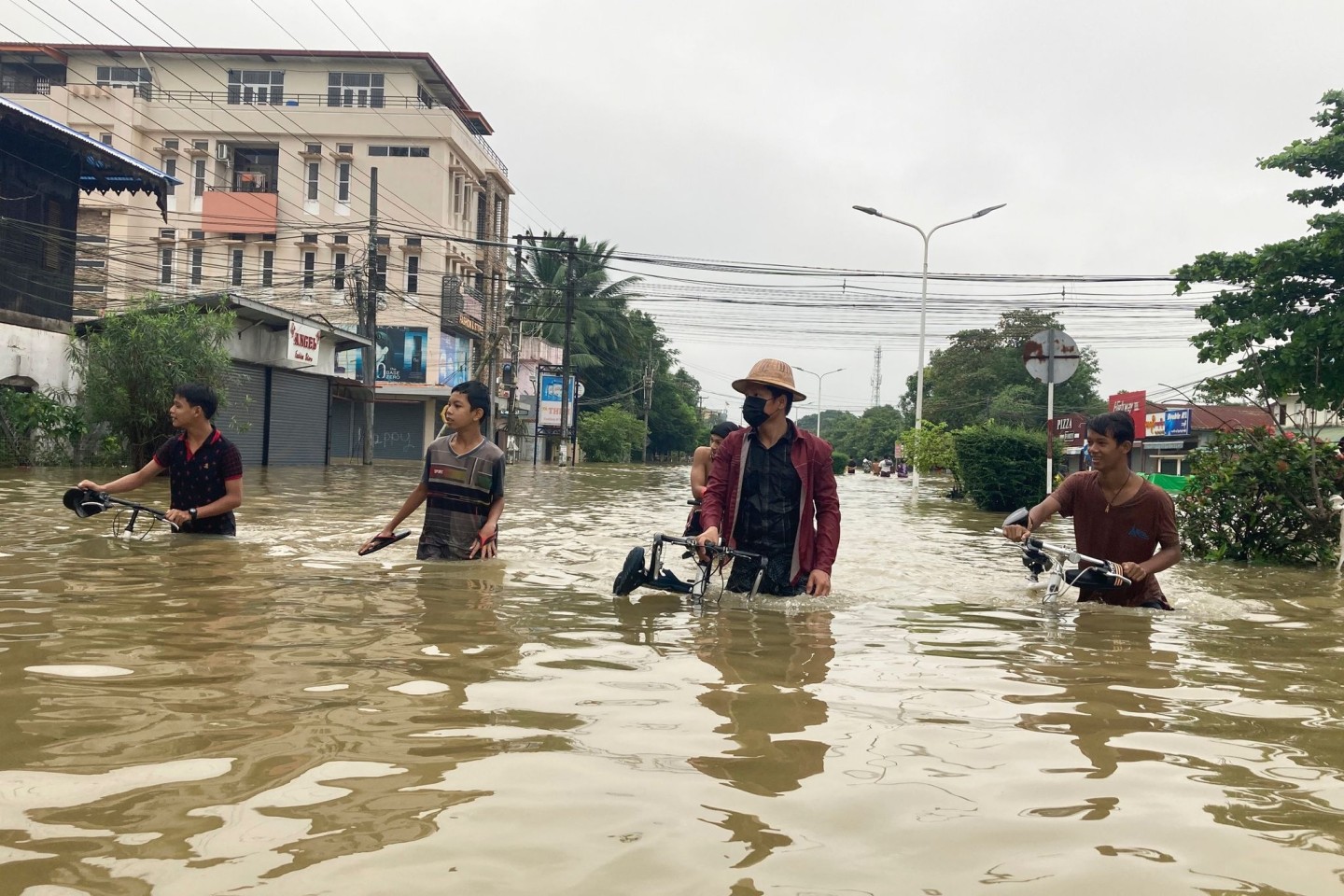 Anwohner schieben ihre Fahrräder durch eine überschwemmte Straße in Bago.