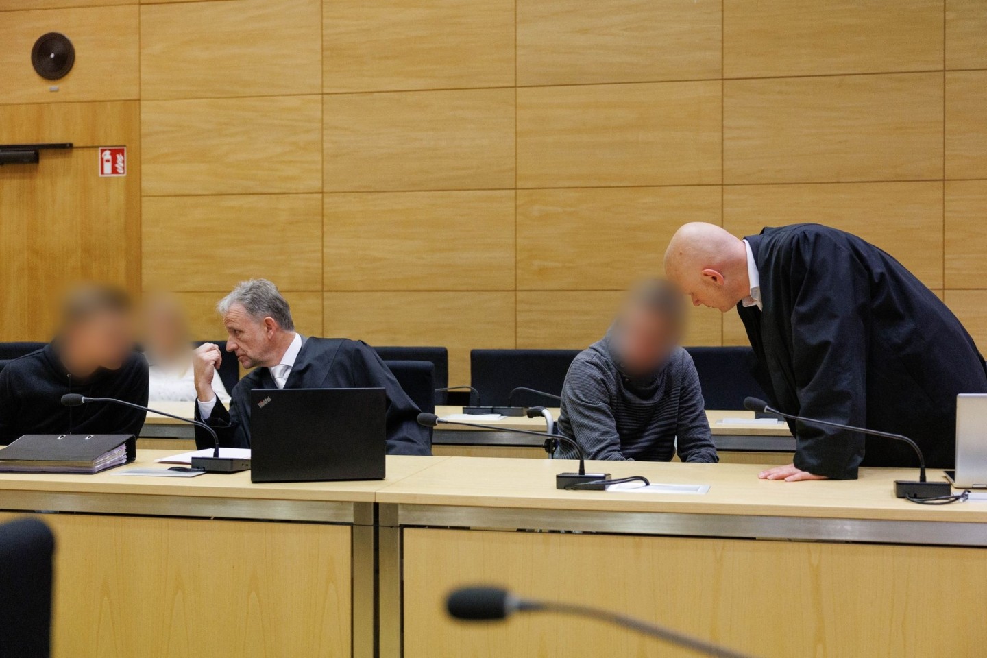 Christian Thüner (2.v.l) und Jerrit Schöll (r), die Verteidiger der Angeklagten, sprechen mit ihren Mandanten in einem Saal des Landgericht Bielefeld zum Auftakt im Prozess um ein illegale...