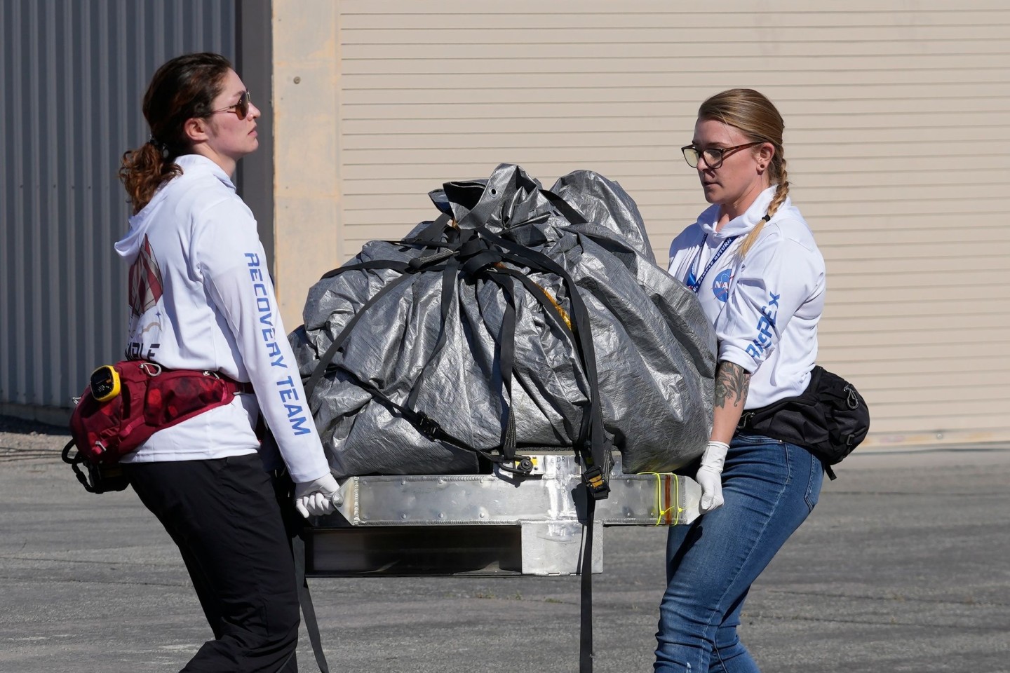 Mitglieder des Nasa-Bergungsteams transportieren die Kapsel mit den Asteroidenproben in ein steriles Labor nahe der Landestelle.